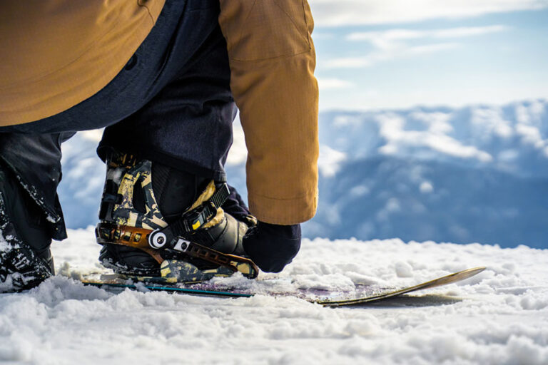 snowboarder straps on a snowboard close up