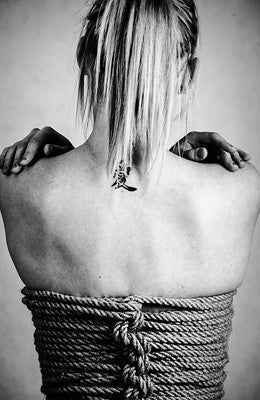 Woman facing away with bondage rope around her torso.