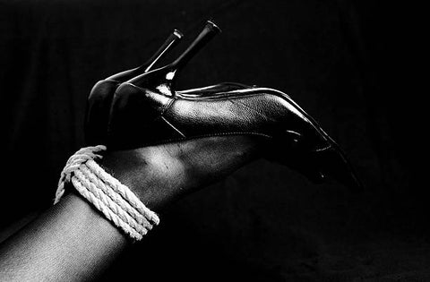 Woman's ankles tied up with a natural fiber rope.