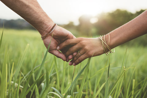 Knotty Desires couple holding hands in a field.