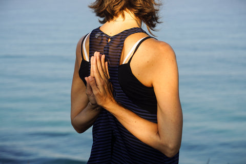 Woman doing Yoga -- Reverse Pray Pose near water.