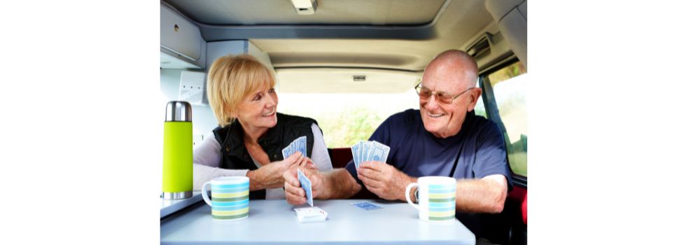 Couple playing cards at table in small RV camper