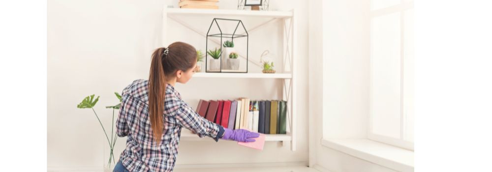 woman cleaning a bookshelf