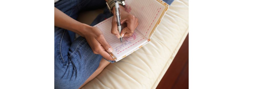 person writing an entry in a journal