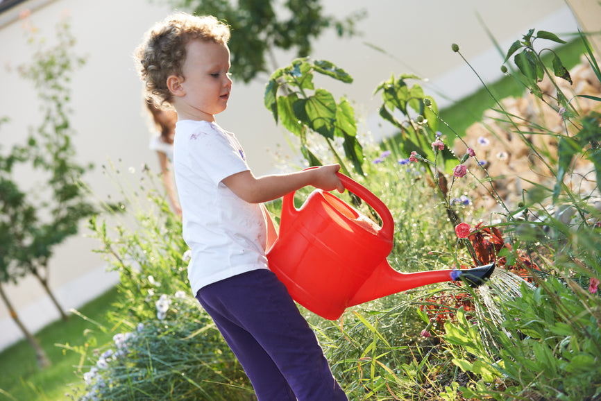child with watering can at gardening