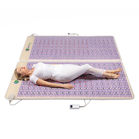 a woman in white relaxes on a taj pemf mat by healthyline