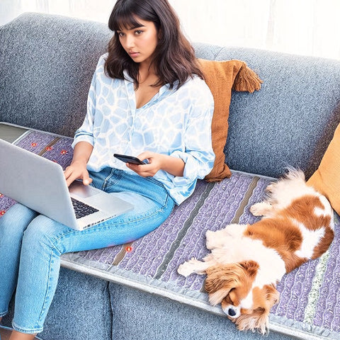 woman sits on PEMF mat with dog