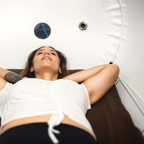 woman enjoys hyperbaric medicine as she lays in a portable chamber