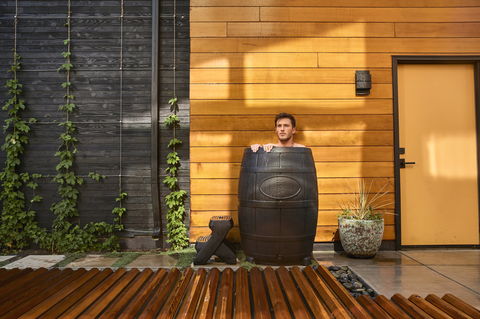 Man doing a cold water therapy treatment in an ice bath. The cold plunge tub is located outdoors on a deck