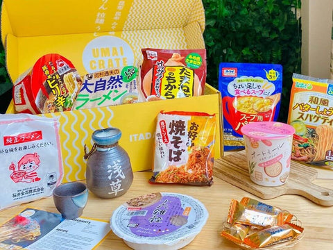 Several cups of ramen and dishes sit in front of an Umai Crate box