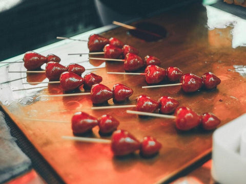 Many sticks of glossy candied strawberries on a shop table