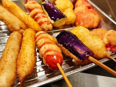 Many fried sticks of kushikatsu with various ingredients sits on a rack