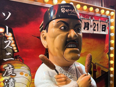 A large display of Kushikatsu Daruma's mascot, the Angry Chef, holding two skewers and looking angry
