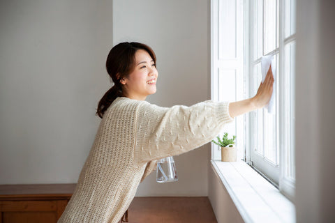 A woman cleans the windows of her home