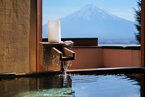 A spout of a hot spring pouring out water in front of Mount Fuji