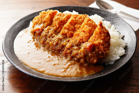 A bowl of Japanese curry and rice with a thick piece of fried pork cutlet on top