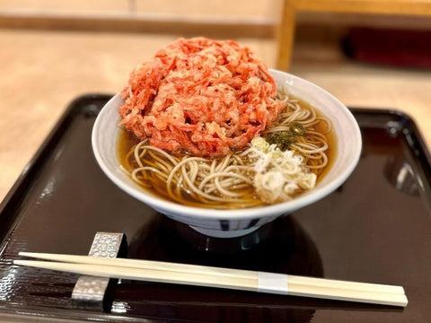 A block of beni shoga tempura sits on top of a bowl of soba