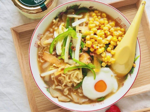 A bowl of ramen with Hokkaido butter, corn, egg, and added vegetables