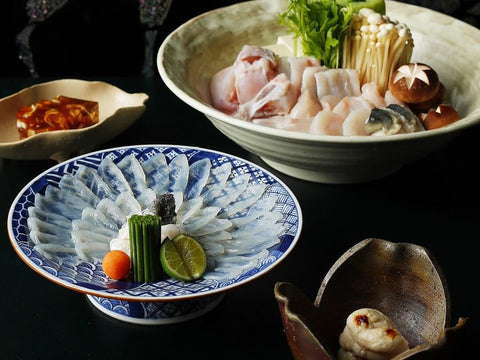 A spread of fugu sashimi, hotpot and fugu roe on a table