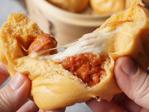 Hands rip a pizza bun to show the marinara and cheese inside