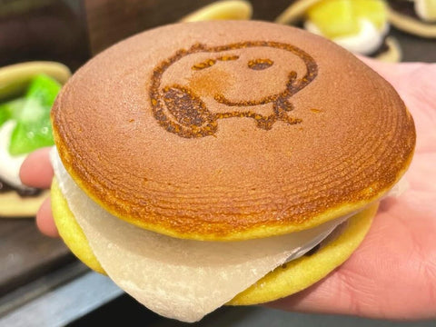 A dorayaki with Snoopy's face on the top and mochi with the red bean paste