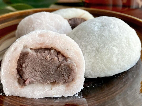 Two larger mochi dumplings split in half to show the red bean paste