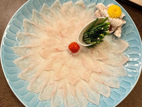 Raw slices of fugu puffer fish laid on a blue plate
