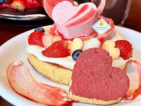 A plate of pancakes with heart-shaped cakes, chocolate, fruit and cream on top