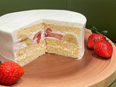 A cake with white frosting and layers of banana, strawberry and cream with the cake