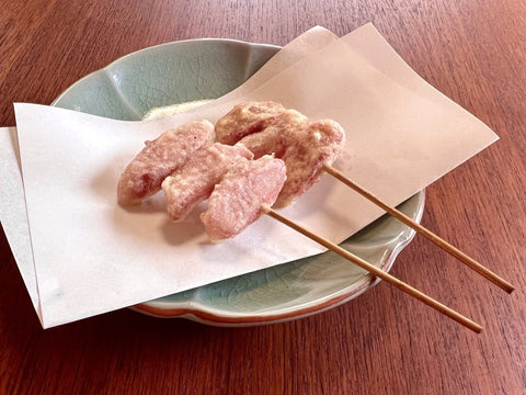 Two sticks of fried red pickled ginger on a plate