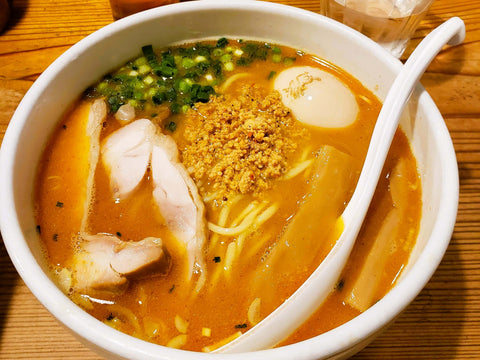 A bowl of spicy chicken ramen in Japan with ground chicken and chicken breast on top