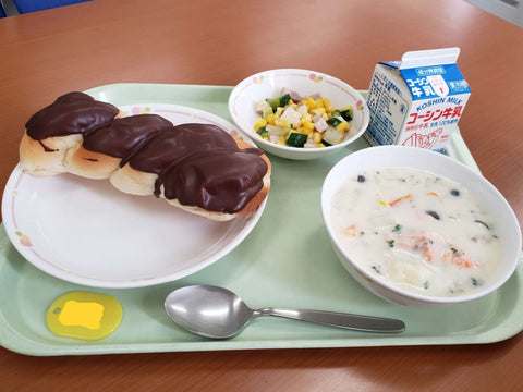 A Valentine's Day Japanese school lunch of chowder, a veggie mix and chocolate bread on a tray with milk