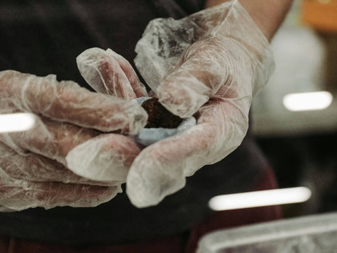 Hands in gloves covered with starch shape mochi around red bean paste