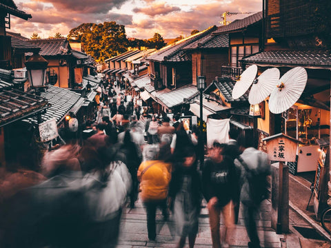 Many people walk along a Kyoto traditional street with many shops