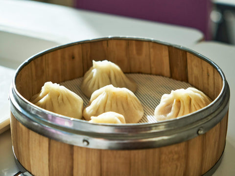 Five Chinese bao buns sit in a steamer basket