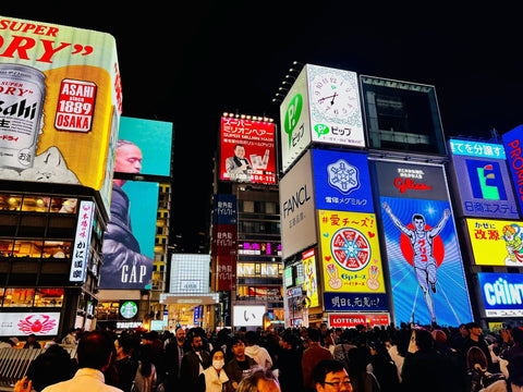 Many signs illuminate Dotonbori Street with Glico Man in the background