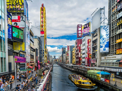Dotonbori canal and all of its shops during the day as a boat travels the canal