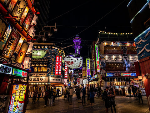 A night scene of Osaka's Shinsekai area with lit up shop signs, 3D billboards and people