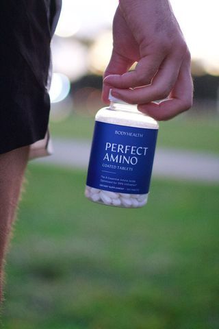 BodyHealth Male Influencer holding a bottle of coated PerfectAmino.