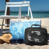 Mermaid Black insulated lunchbox and Ocean Blue tote bag on the beach