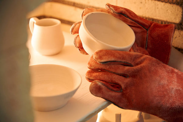 holding a pottery cup with gloves