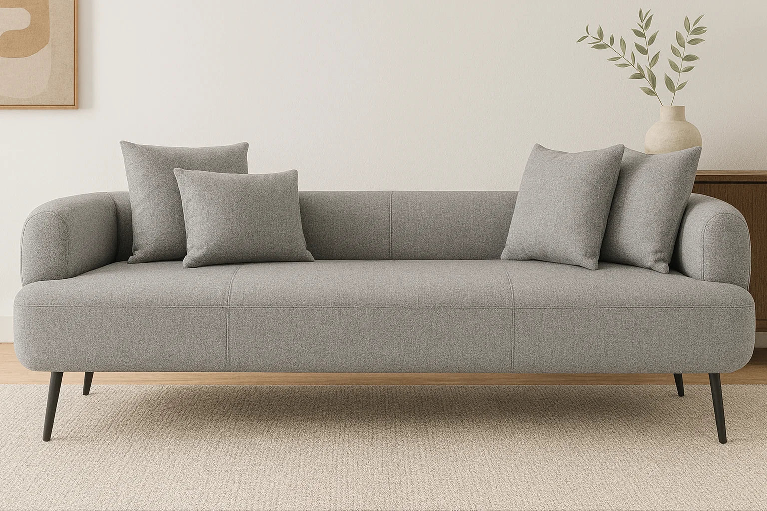 Sofá gris moderno de tres plazas en sala luminosa con decoración minimalista y arte abstracto en la pared.