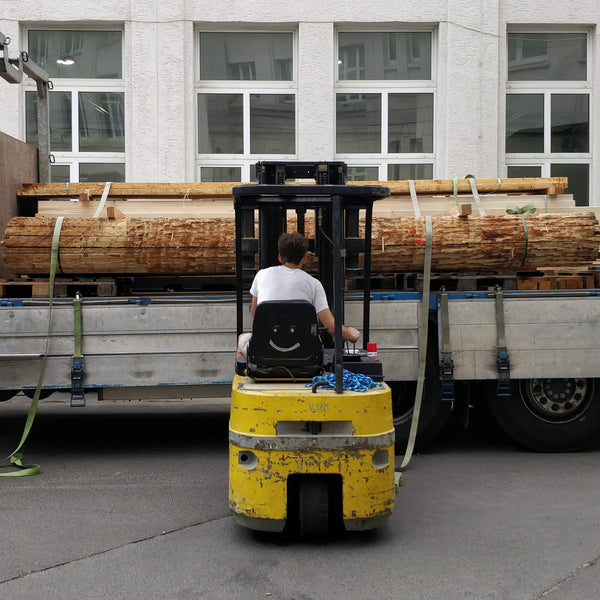 Ein Gabelstapler lädt Holz von LKW ab auf dem Innenhof der Werkstatt von BARTMANN in Berlin-Tempelhof