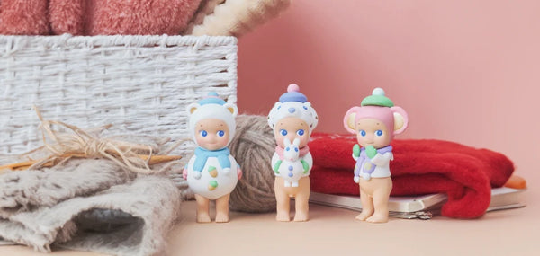 Three Winter Series figures next to a knitting basket