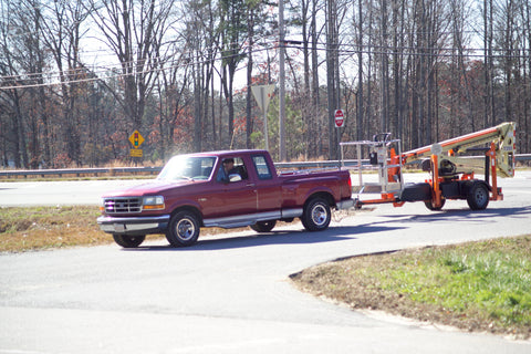 A JLG T350 Towable boom lift being towed by truck.