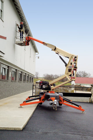 A JLG T350 Towable Boom Lift being used to work on the side of an industrial building
