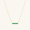 Baguette Emerald Bar Necklace: A gold necklace featuring a handcrafted rectangular emerald pendant with unique inclusions, set on a fine chain.