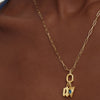 Person wearing an Oval Charm Enhancer gold necklace with a blue stone pendant, showcasing its elegant design and versatility for various styles.