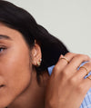 Close-up of a woman's face showcasing Patra Huggie Hoops, handcrafted 14k gold earrings, highlighting their elegant design.