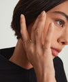 Woman wearing a Bezel Emerald Half Eternity Band, showcasing a 14k solid gold band with bezel-set emerald gemstones.